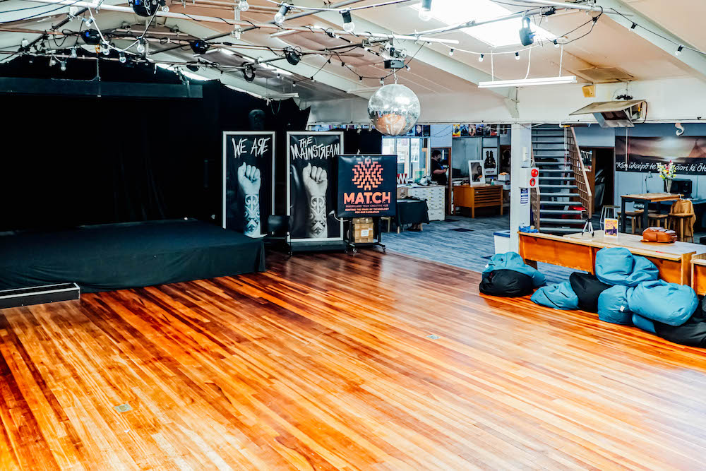 Wooden floor, stage, beanbags and disco ball inside the Māoriland Hub