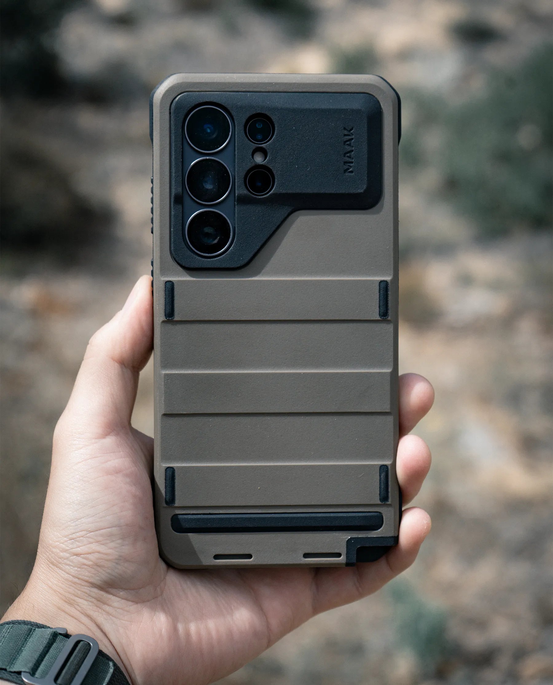 A rugged MAAK Forge phone case held outdoors