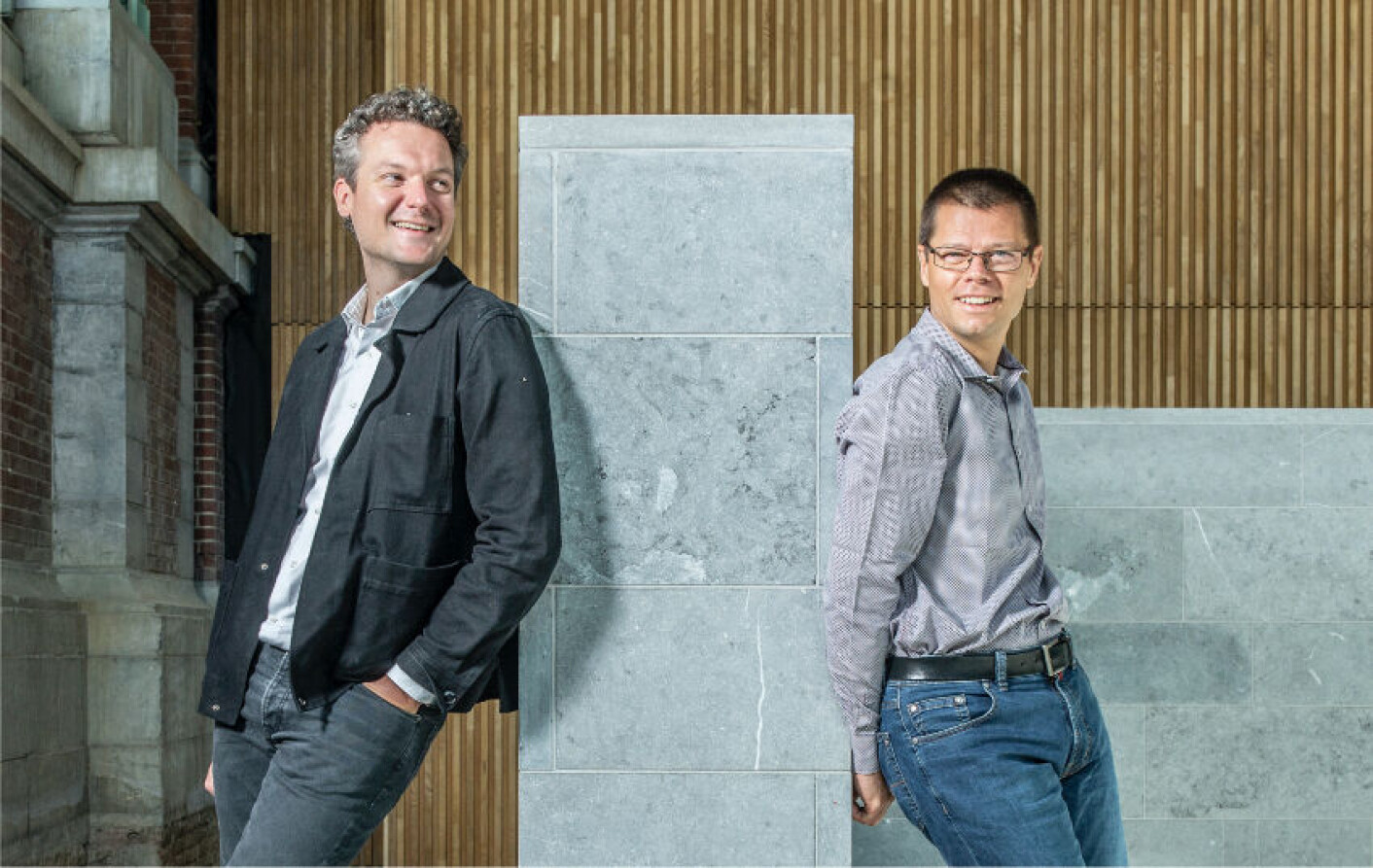 Maarten Masschelein and Tom Baeyens standing back to back outside a modern building