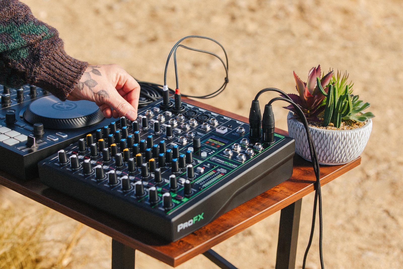A person using a battery-powered Mackie ProFX GO mixer outdoors