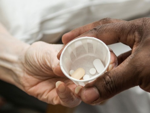 Close-up of hands passing medication from one person to another