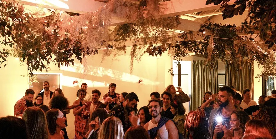 Guests gather beneath hanging foliage at a FARM Rio event shown in MAD’s portfolio