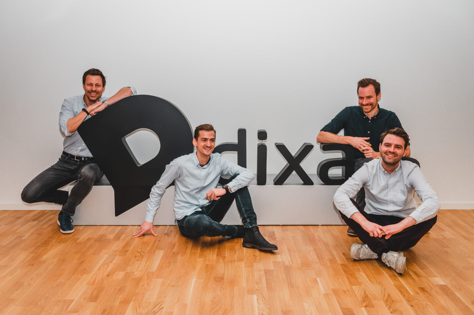 Dixa’s four co-founders gathered around a large Dixa sign, with Mads Fosselius at the left