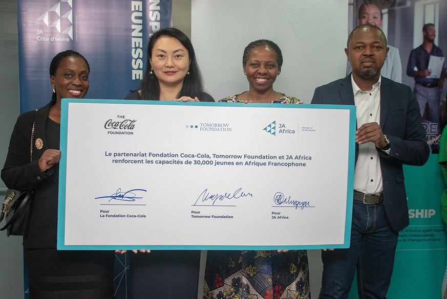 Maggie Gu and partners hold a signed board announcing expanded skills training for 30,000 young people in francophone Africa