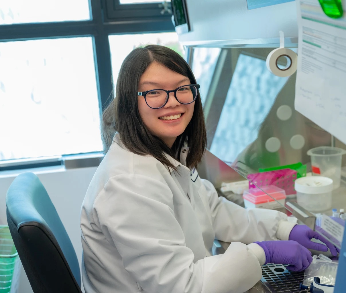 Scientist in a white lab coat using a pipette amid laboratory equipment