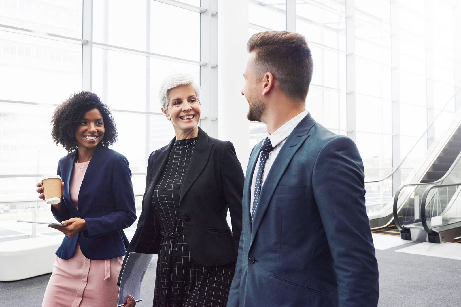Three professionals in conversation in a bright office setting
