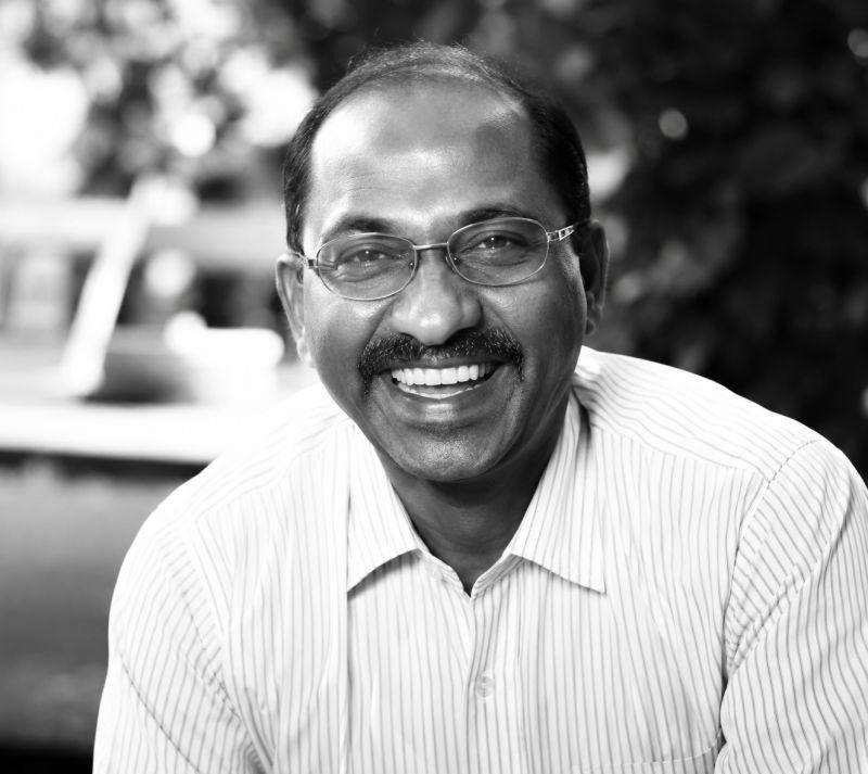 Mahesh Niruttan smiling in an informal black-and-white photograph