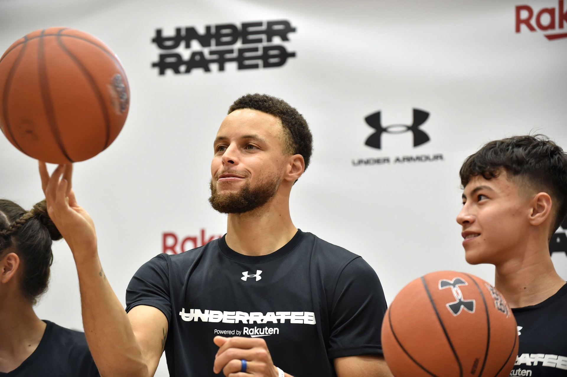 Stephen Curry spinning a basketball at the Underrated Tour activation backed by Rakuten