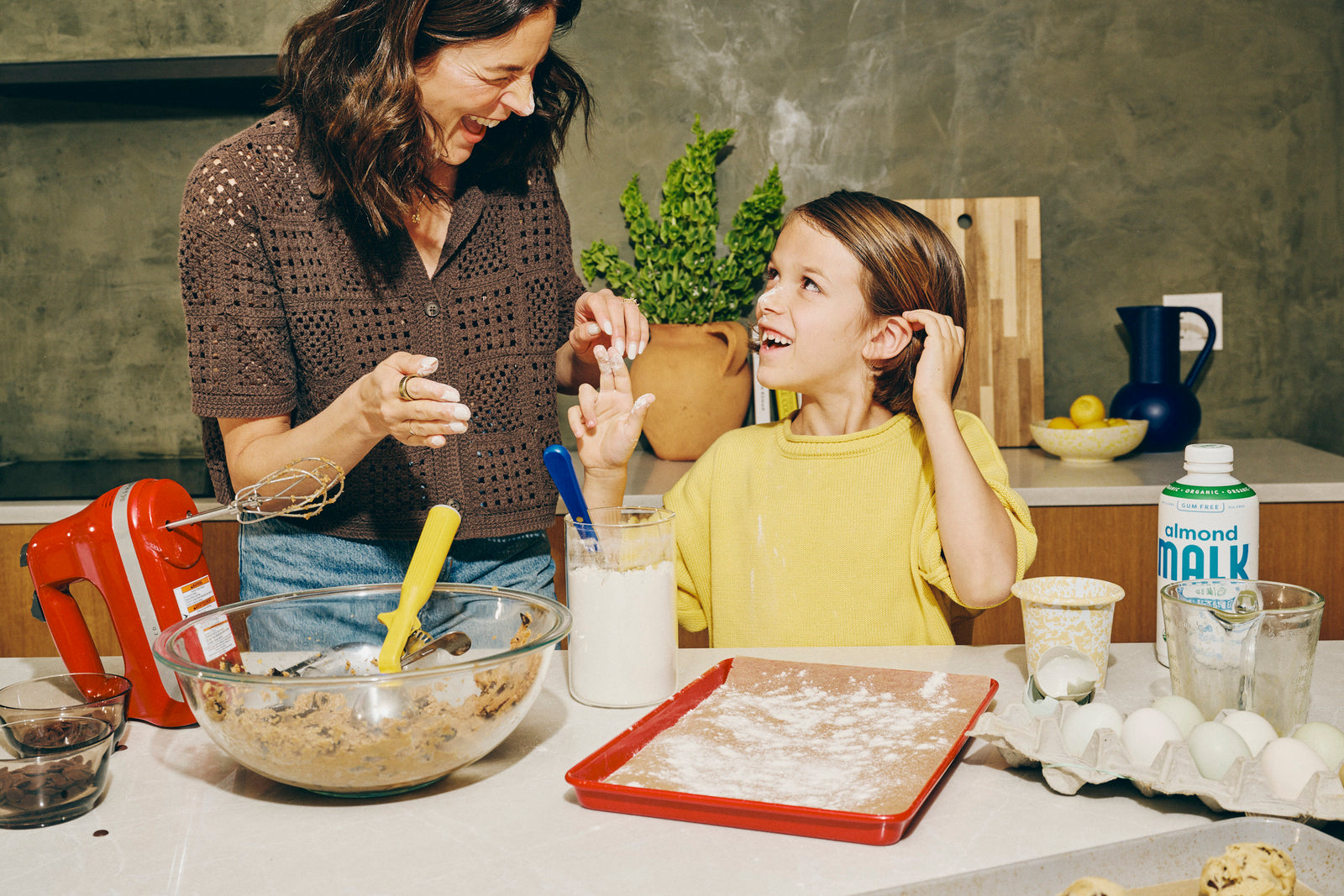 A mother and child baking with MALK almond milk in a kitchen