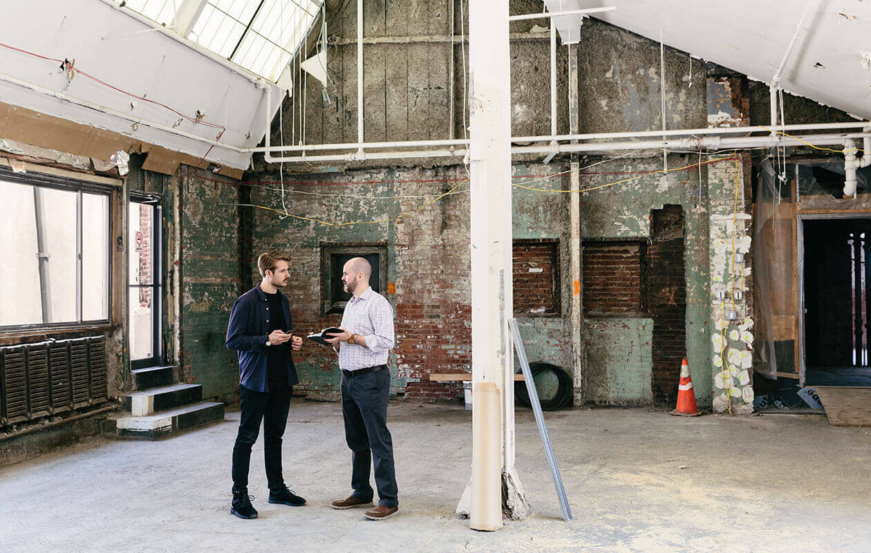 Dan Teran and Jason Havens discussing an office project in an unfinished interior