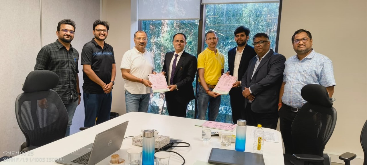 Representatives holding signed documents around a meeting table in the photograph accompanying Prozeal’s Grasim announcement