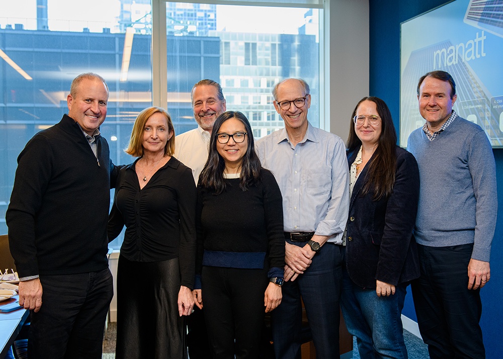 Seven Manatt colleagues gathered in a bright New York office during the firm’s anniversary celebrations