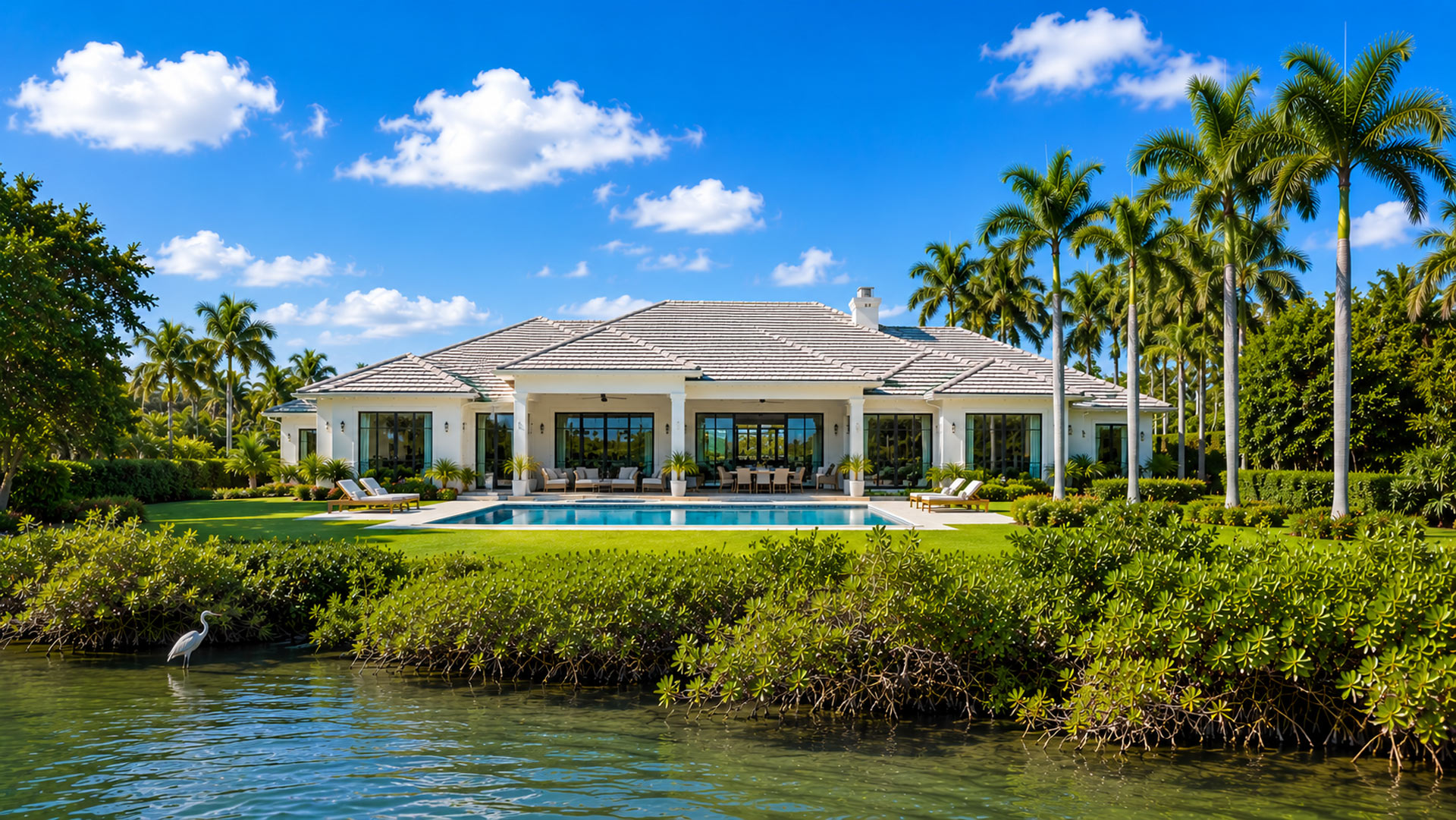 A Florida home beside mangroves and water under a bright sky