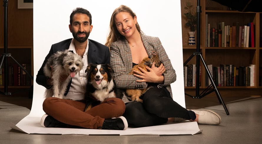 Manick Bhan and a companion sitting with two dogs and a chicken during a studio photograph