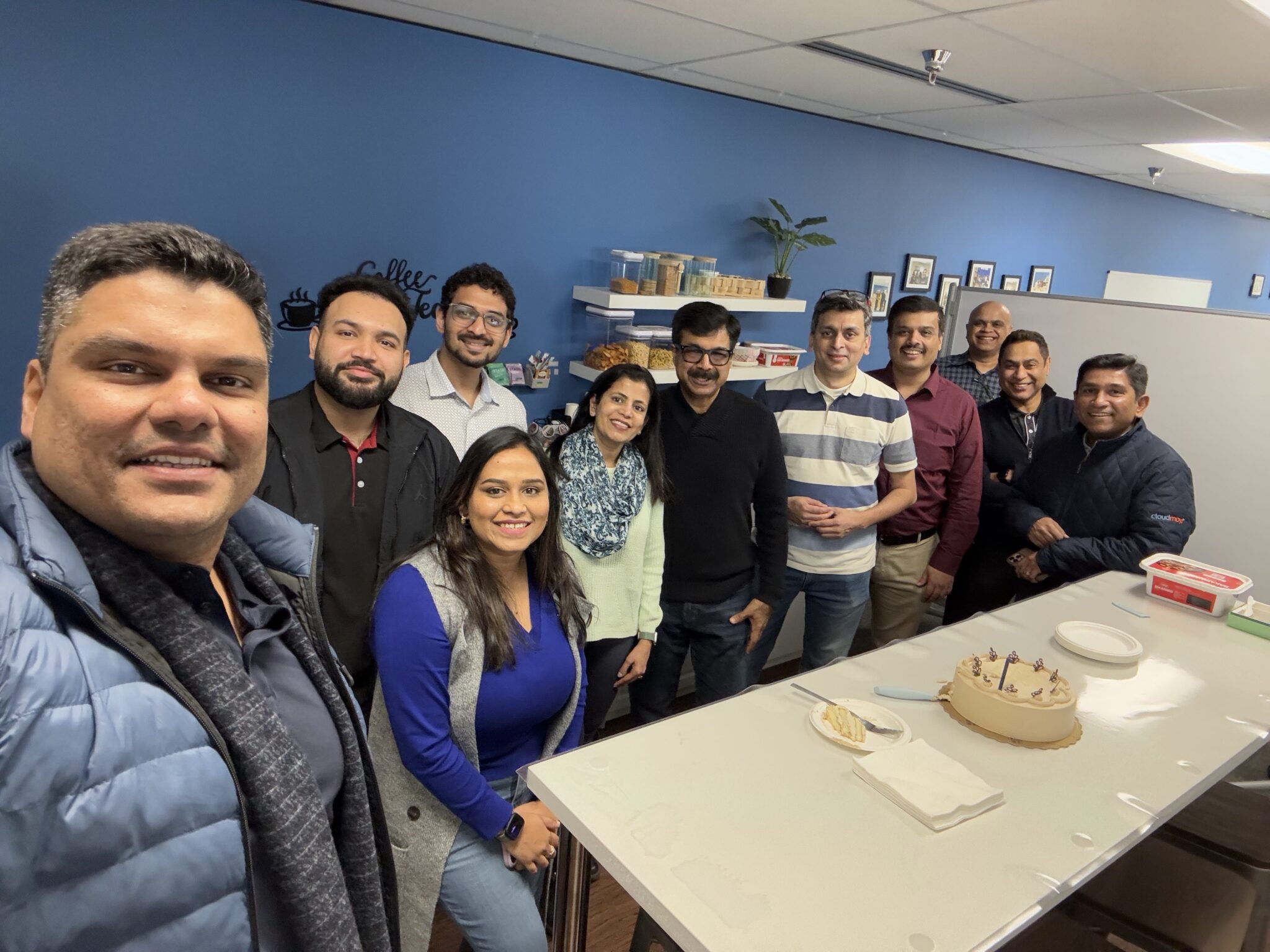 Manish Kedia and CloudMoyo colleagues gathered around a cake in the Bellevue office