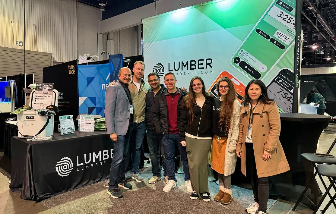 Manish Kumar and six Lumber colleagues standing at the company's trade-show booth