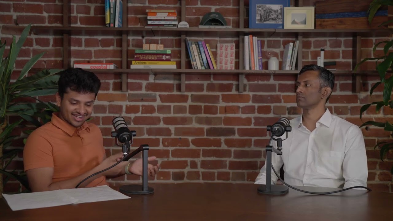 Abhinav Singh on the left interviews Manoj Gopalkrishnan on the right at a table with microphones.