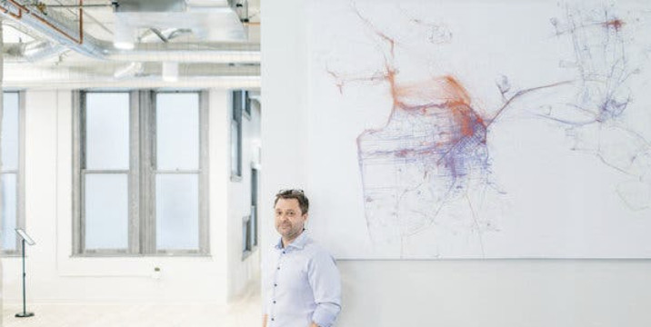 Mapbox co-founder Eric Gundersen standing beside a large map in an office