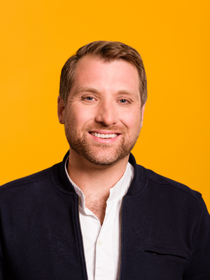 Marc Boxser in a press portrait against a yellow background