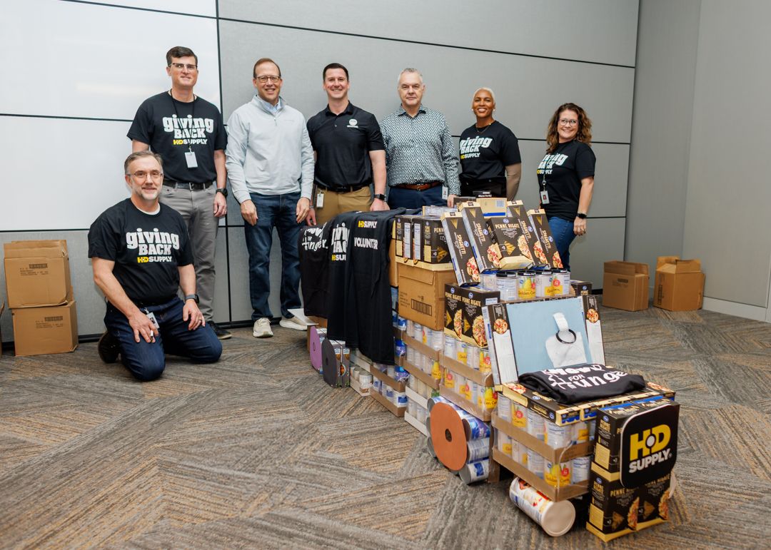 Seven volunteers beside a truck-shaped display made from food packages and boxes.