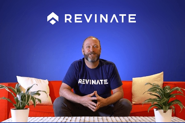 Marc Heyneker seated on an orange sofa in a Revinate shirt, discussing the company’s guest data platform