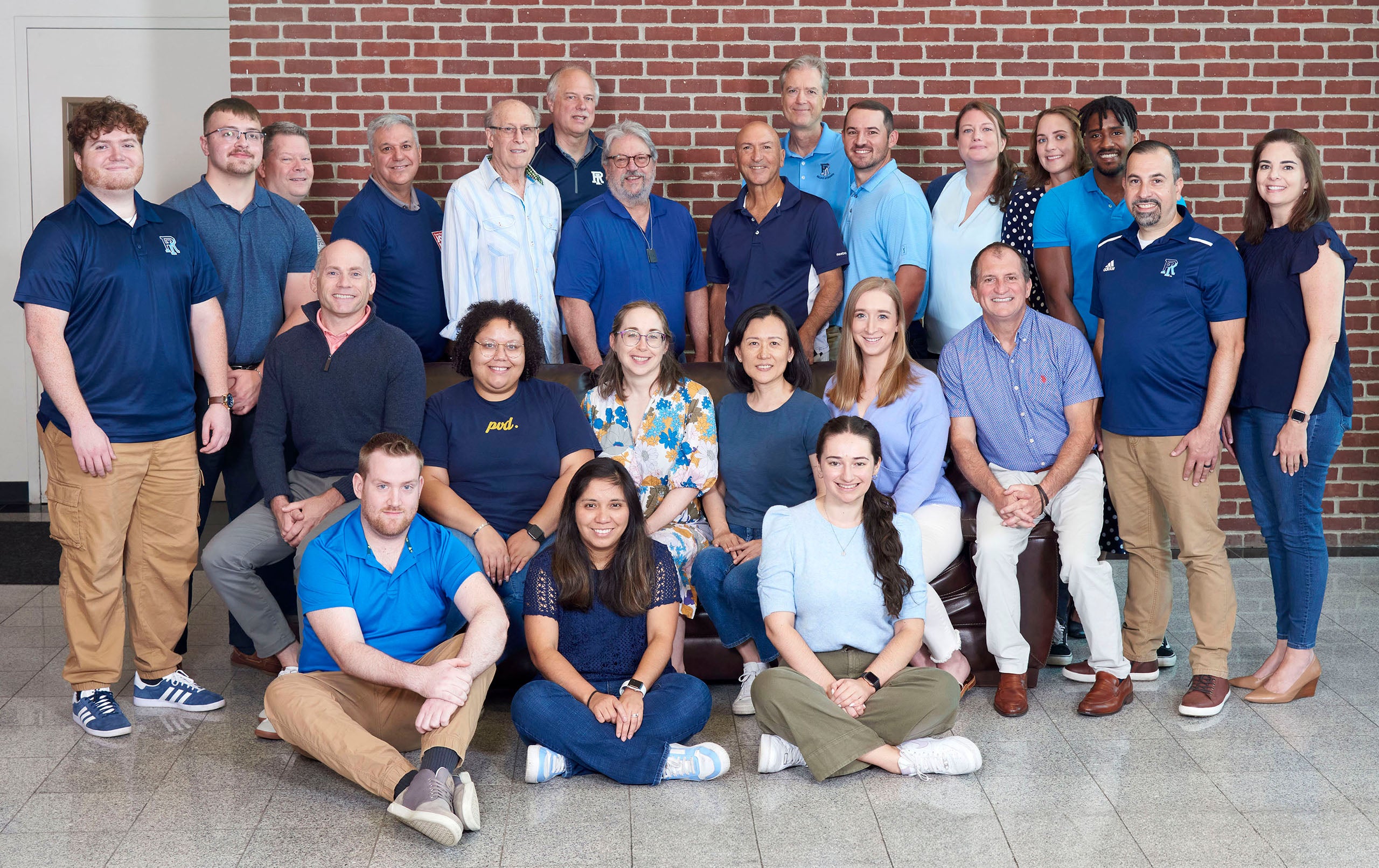 Marc Perlman, standing near the center in a blue shirt, with Ocean State Job Lot colleagues who are University of Rhode Island alumni.