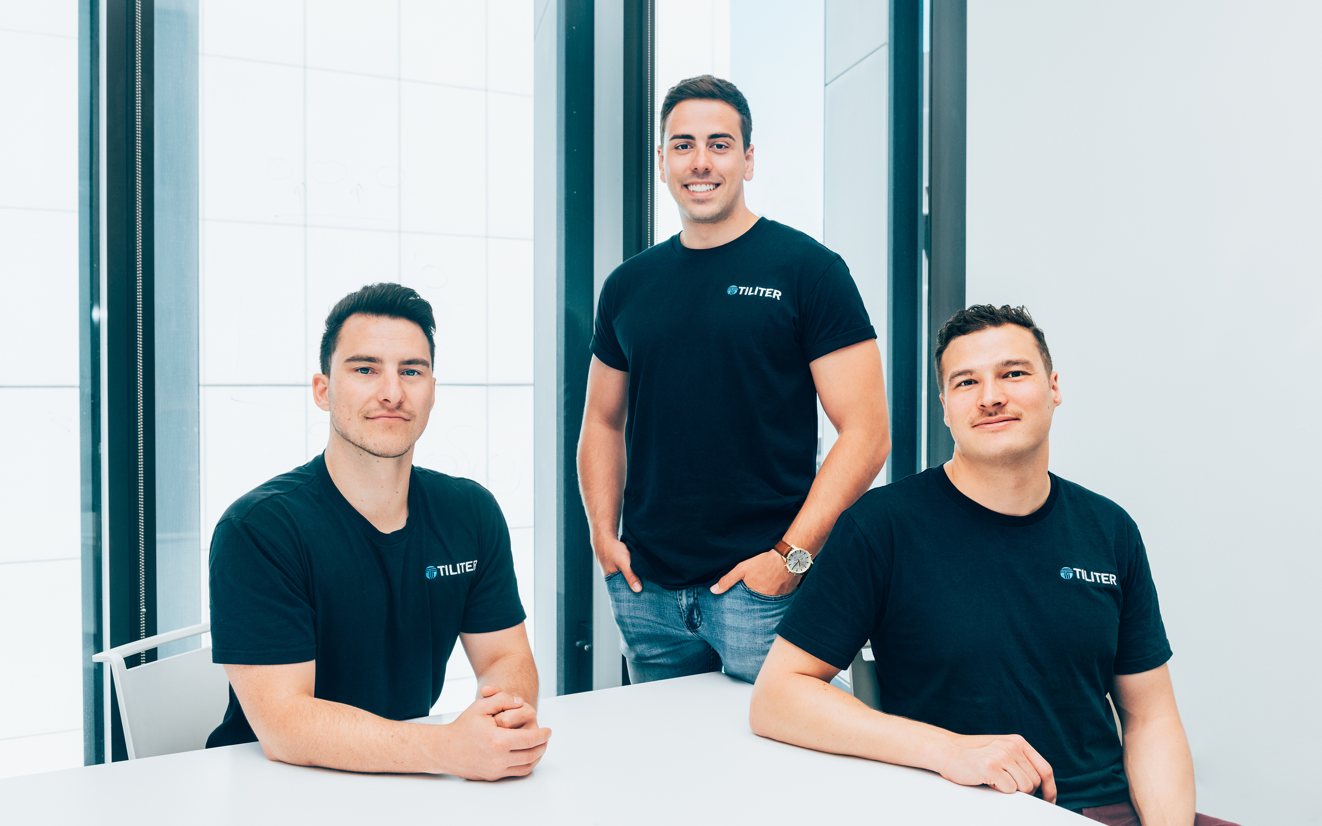 Tiliter co-founders Christopher Sampson, Martin Karafilis and Marcel Herz seated and standing together in an office