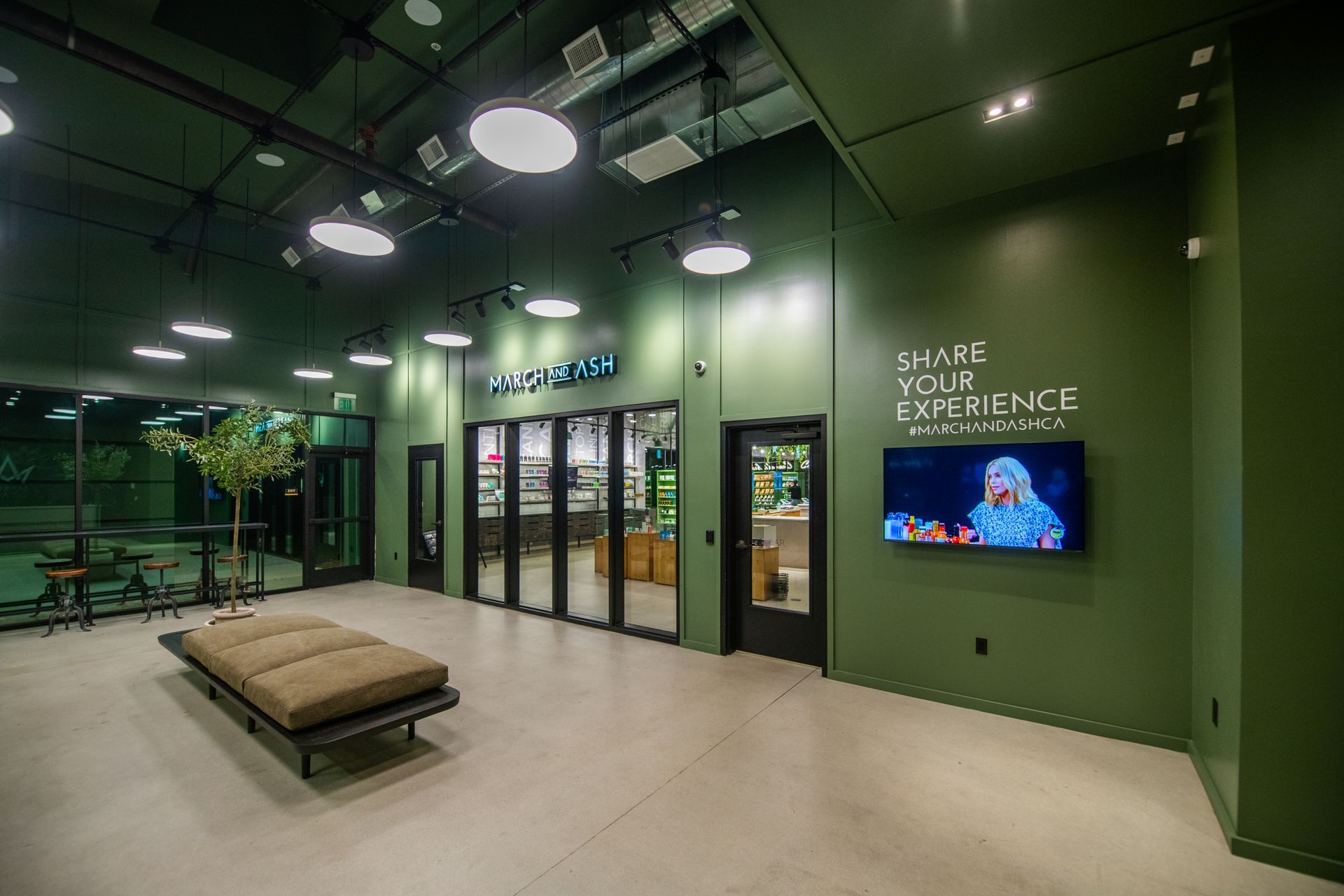 Forest-green interior of a March and Ash dispensary with product room beyond glass doors