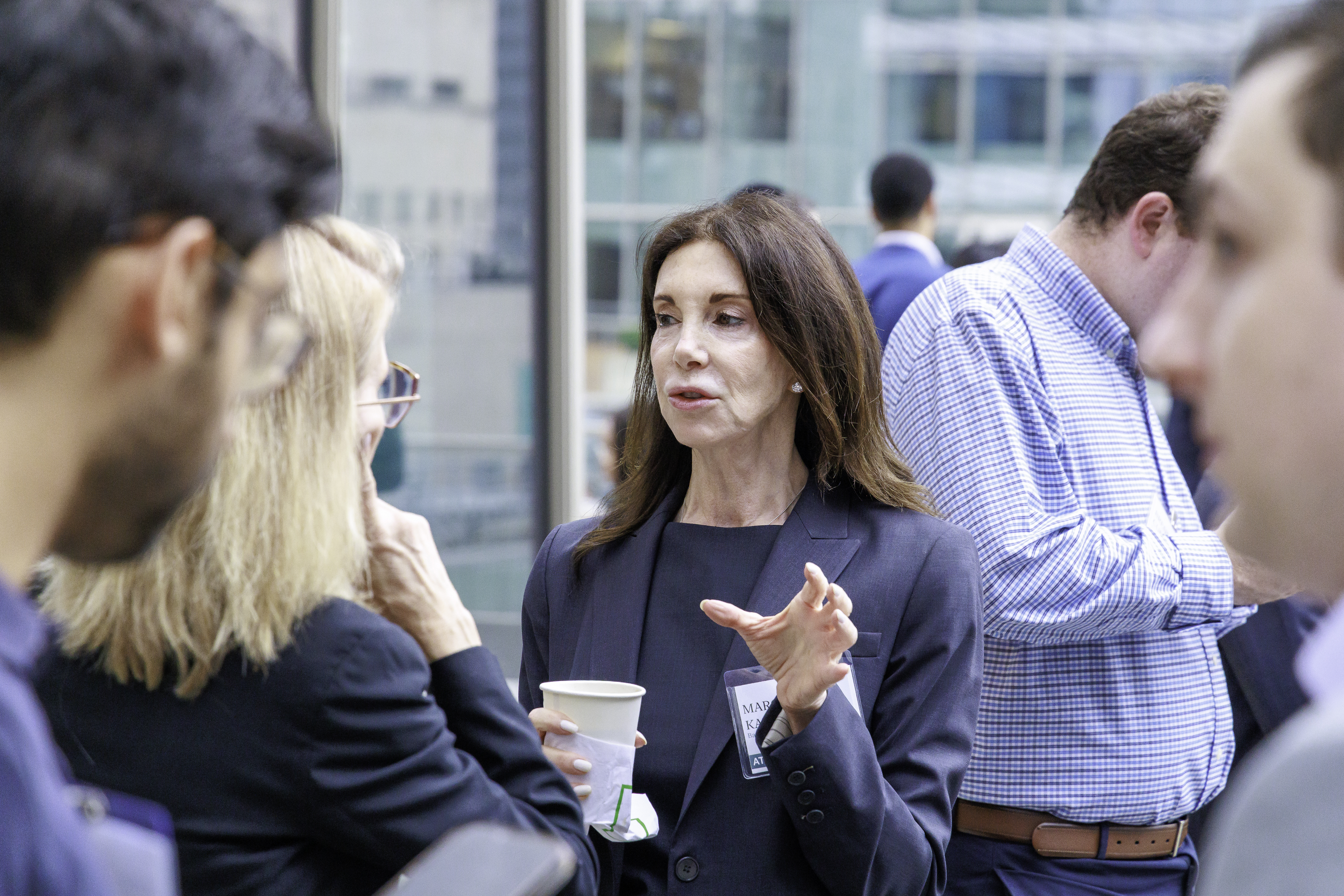 Marcia Kaufman talking with attendees, holding a coffee cup, at Coffee & Cap Rates in New York
