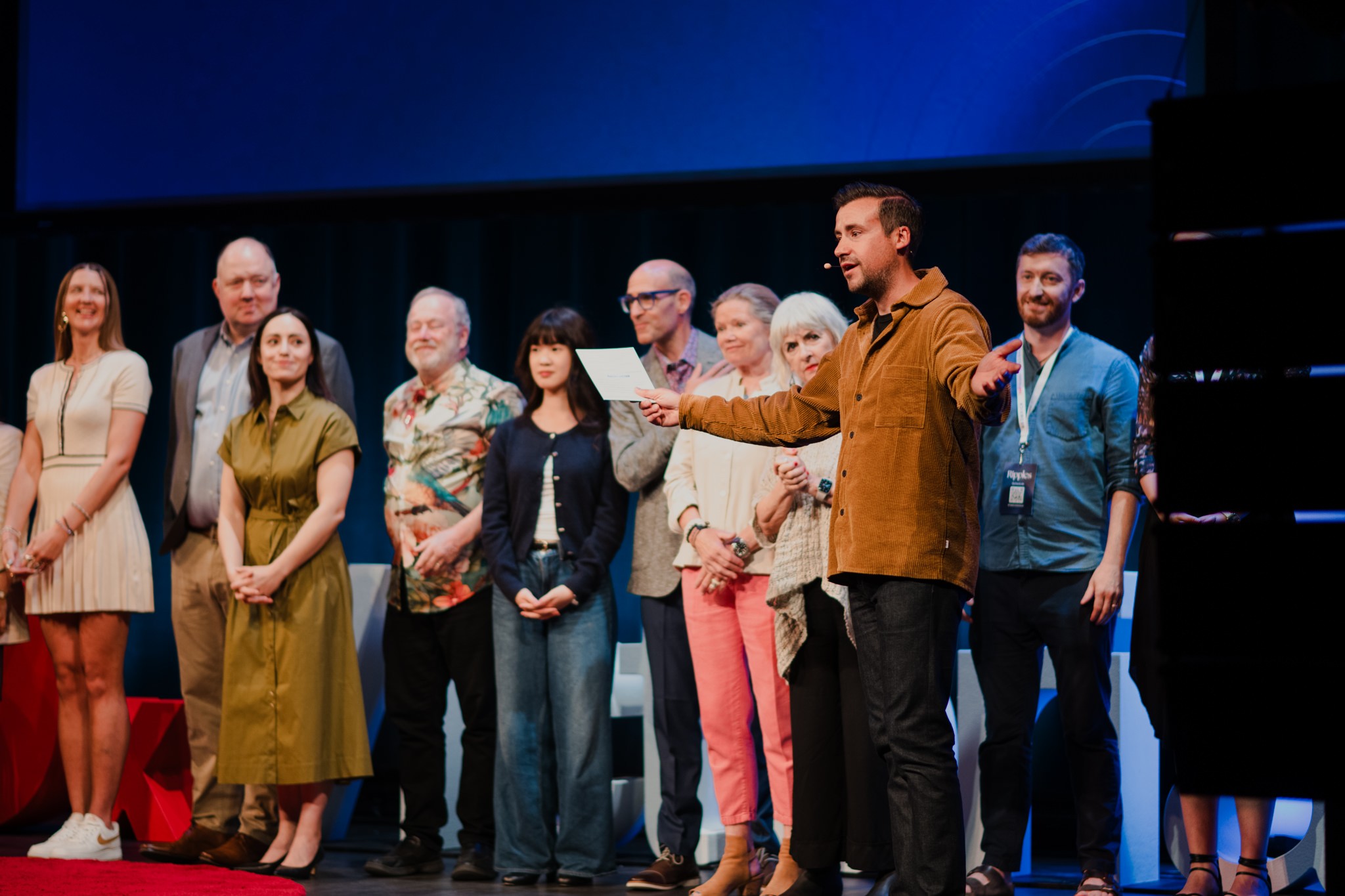 Marco Pimentel speaking onstage with the TEDxVictoria team behind him