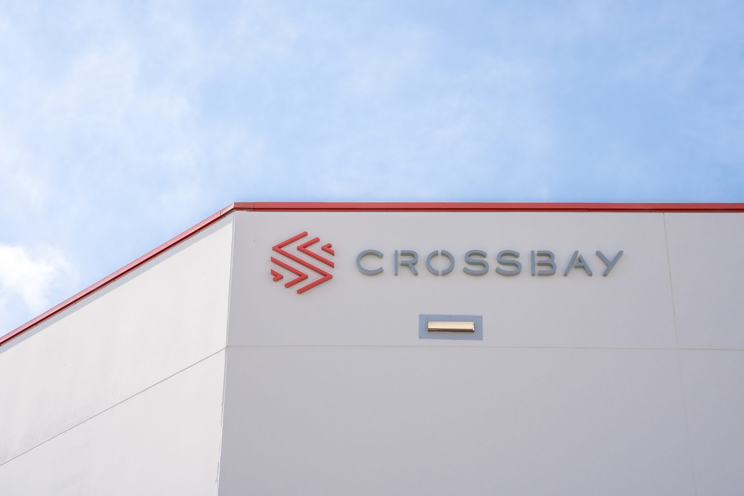 Crossbay branding on the exterior of a warehouse beneath a blue sky