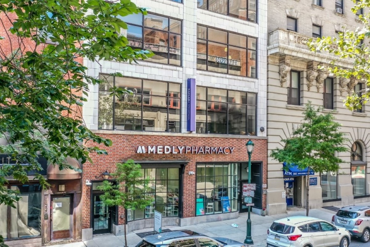Medly storefront on a New York street, with apartments above and cars outside