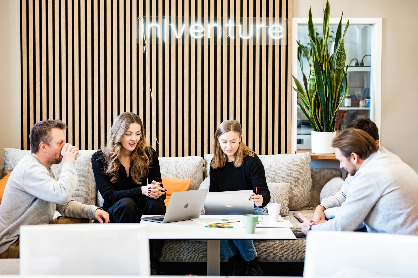 People with laptops gathered around a table beneath an Inventure sign