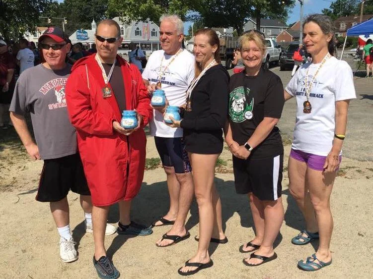 Minuteman Masters swimmers with medals after the 2017 Mighty Merrimack Swim; Maria Beconi stands at the far right.