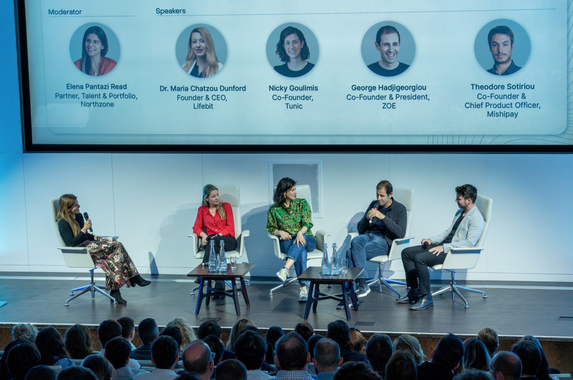 Maria Chatzou Dunford, second from left, in a red jacket on a five-person discussion panel in London