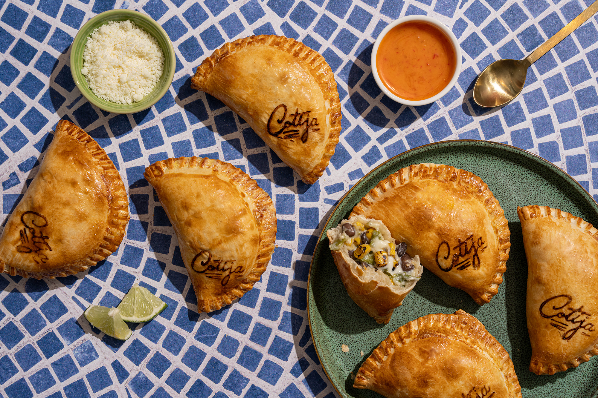 Overhead spread of Maria Empanada empanadas with dipping sauces on tile