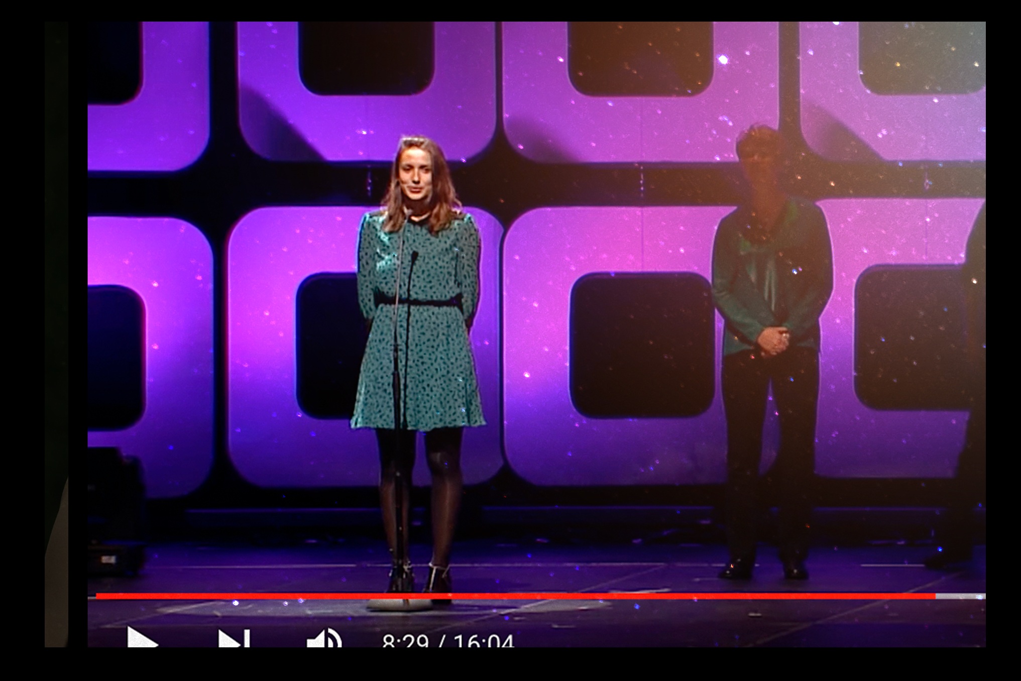 Maria Fujihara speaking on a purple-lit stage