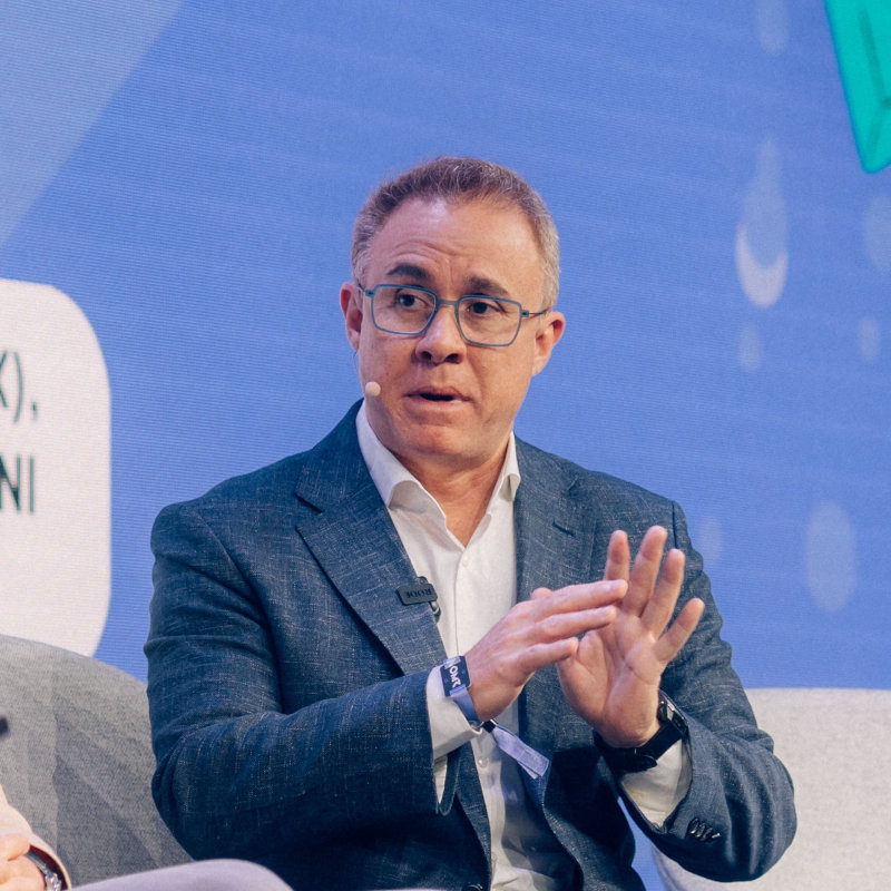 Mariano Gomide de Faria speaking on an OMR panel, gesturing with his hands