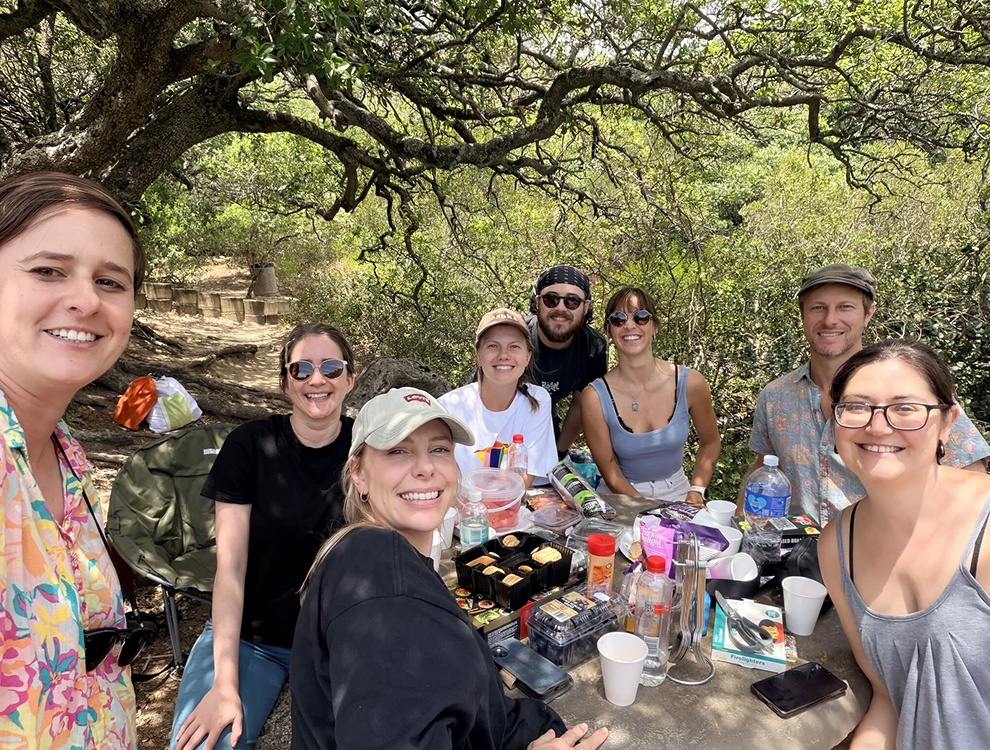 Pepperplane colleagues gathered around an outdoor table beneath trees