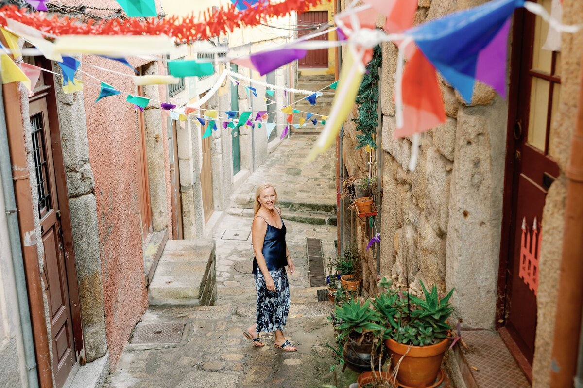 Marilyn Olson walking in a narrow, flag-strung lane in Porto, Portugal