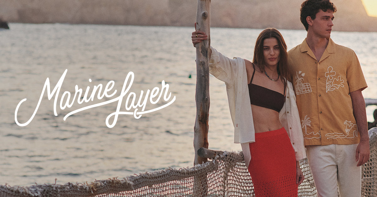 Marine Layer brand imagery with the Marine Layer wordmark, two models in casual apparel by the coast