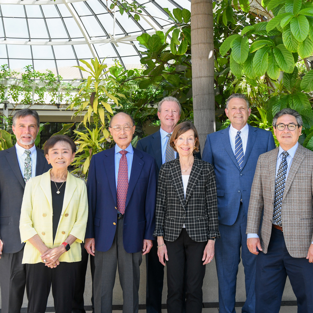 Seven Huntington trustees stand together beneath a glass dome among tropical plants. J. Mario Molina is second from right.
