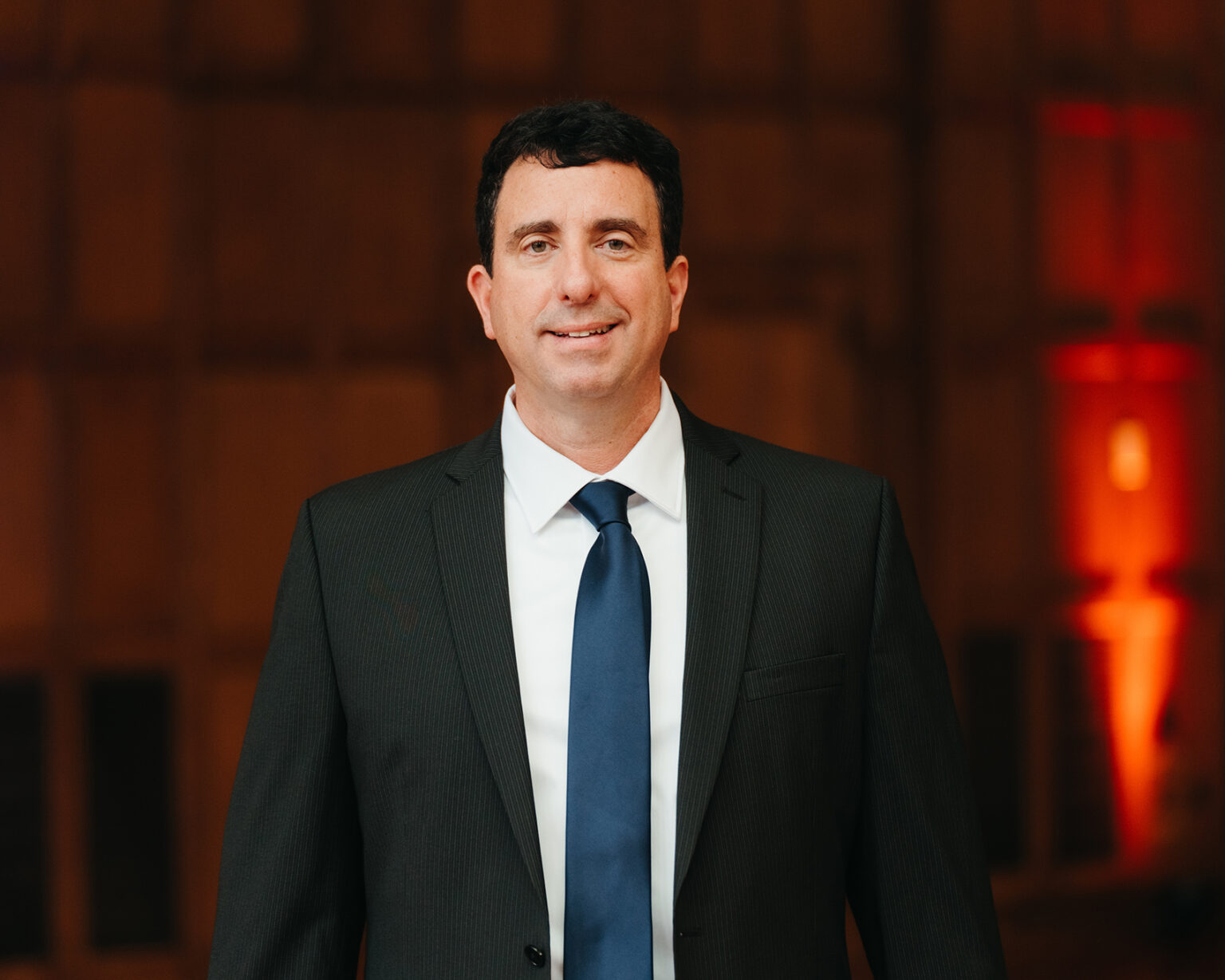 Mario Paniccia in a dark suit and blue tie at a formal industry event