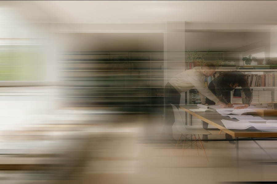 Two people work across a table in a motion-blurred creative office