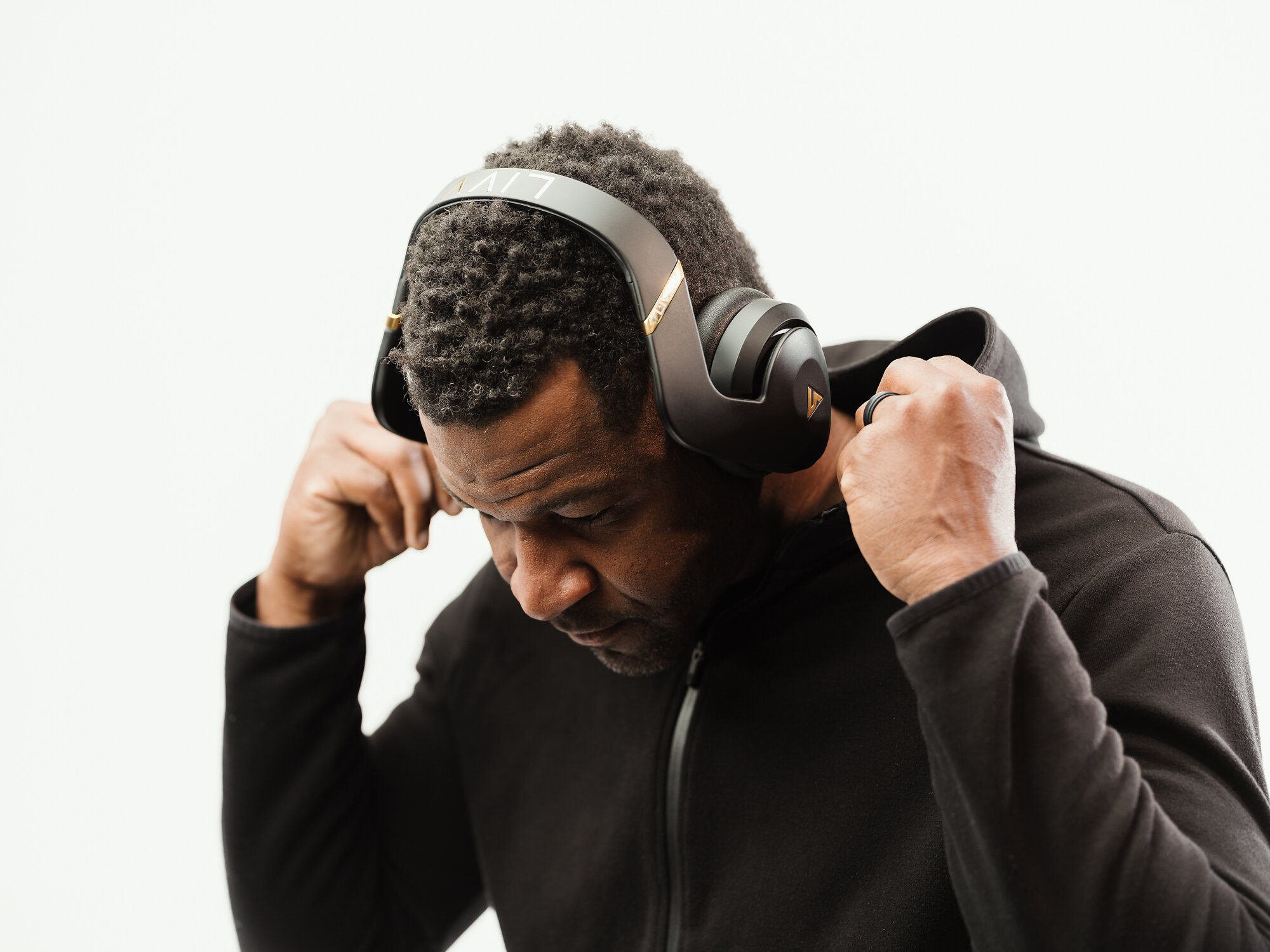 Mark Clayton wearing black LIVV Pro headphones while pulling up the shoulders of his hoodie