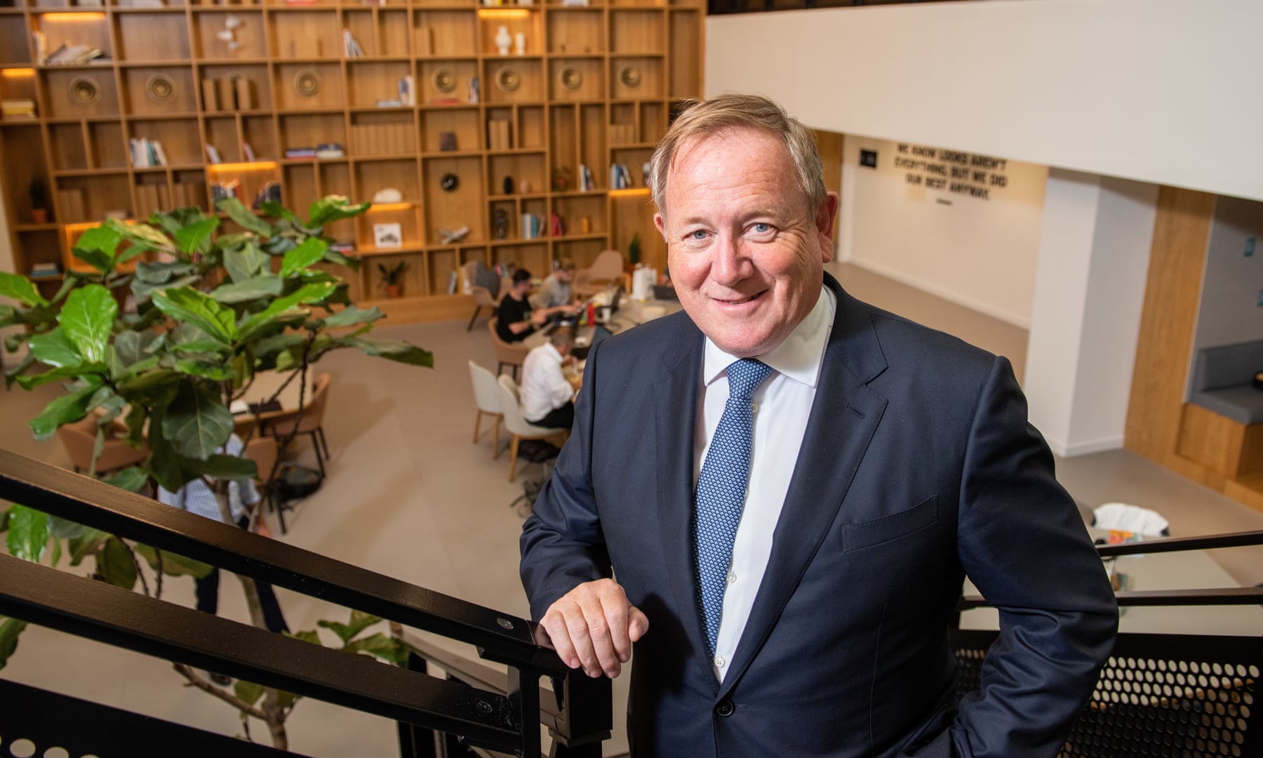 Mark Dixon standing beside a staircase overlooking a furnished workspace