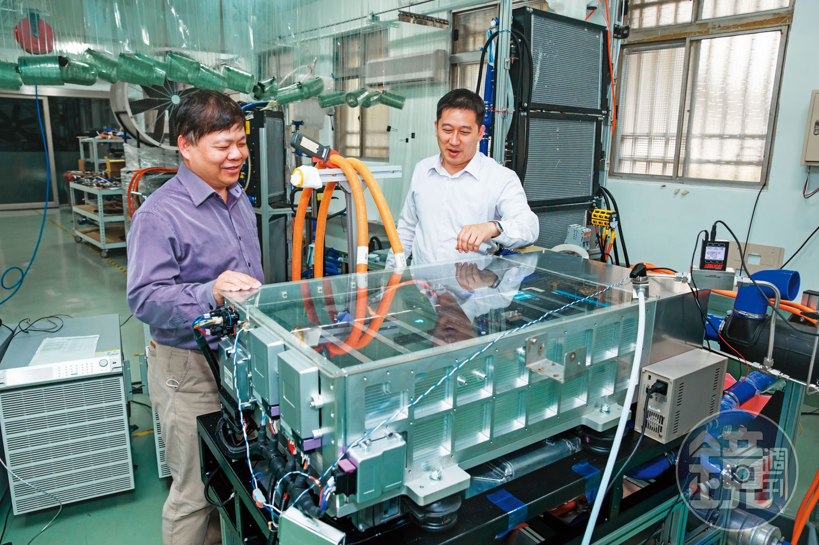 Mark Huang examining a hydrogen fuel-cell power system with a colleague in a workshop