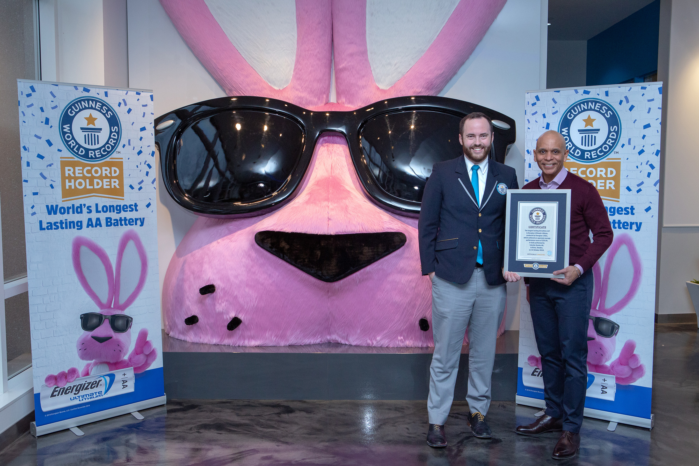 Guinness World Records adjudicator Mike Marcotte and Energizer technology executive Terence Calloway with a battery-record certificate in front of an oversized Energizer Bunny display