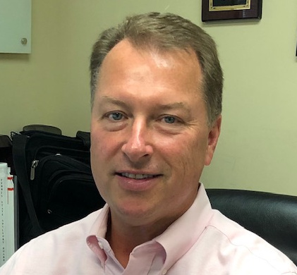 Mark McLochlin seated in an office, wearing a light pink shirt