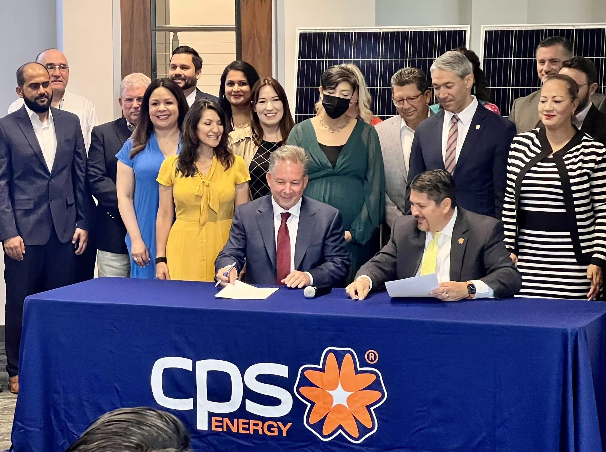 Mark Noyes, at left, signs a solar agreement as CPS Energy interim CEO Rudy Garza watches